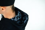 Patterned lining inside the black hoodie's hood, from behind