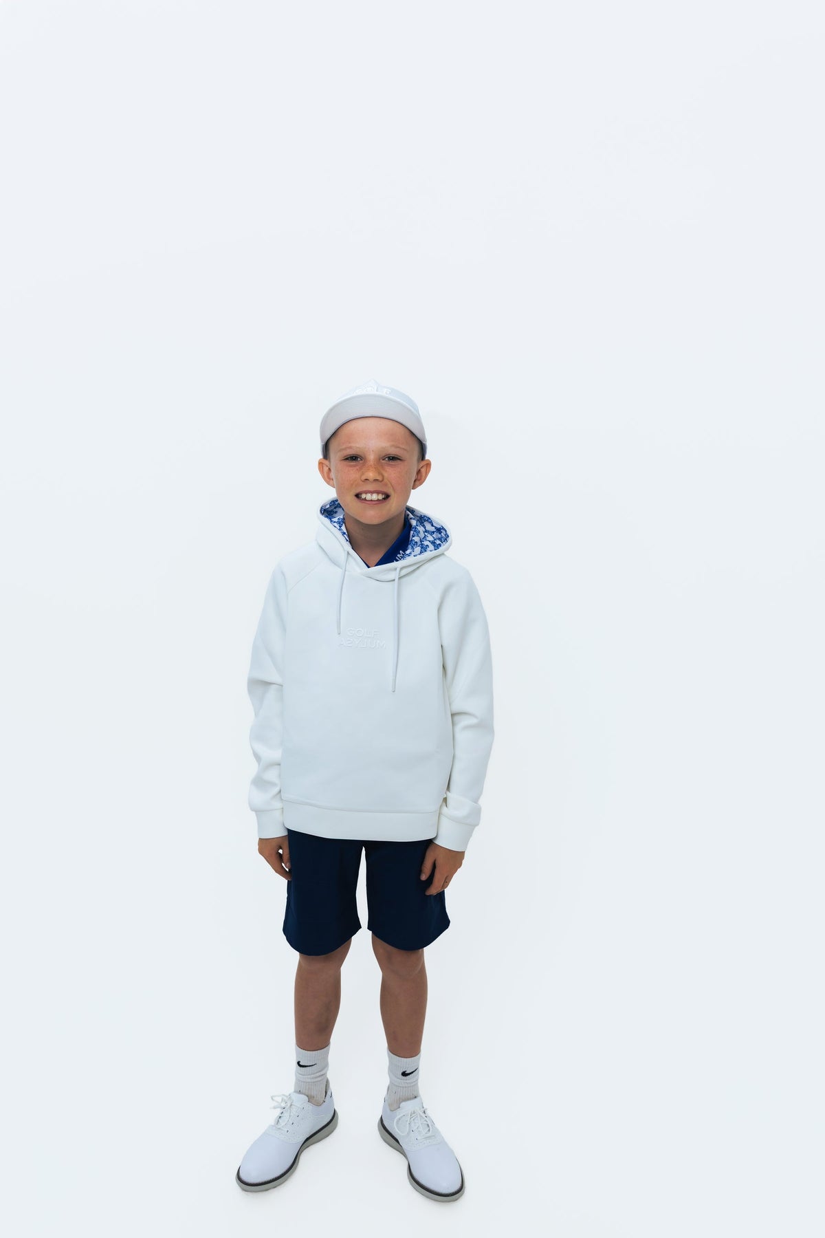 Junior golfer in a white Golf Asylum hoodie
