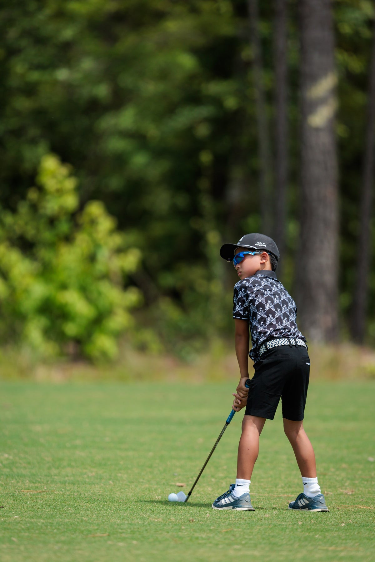 Junior golfer in sunglasses lining up a shot at the Golf Asylum Invitational