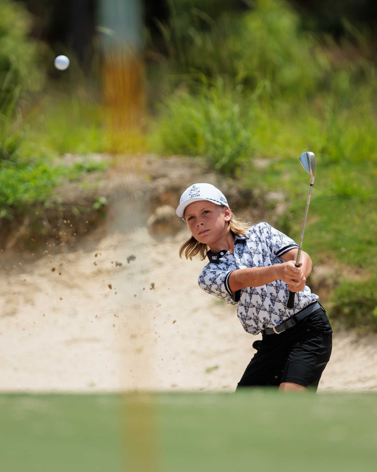 Junior golfer playing out of a bunker at the Golf Asylum Invitational