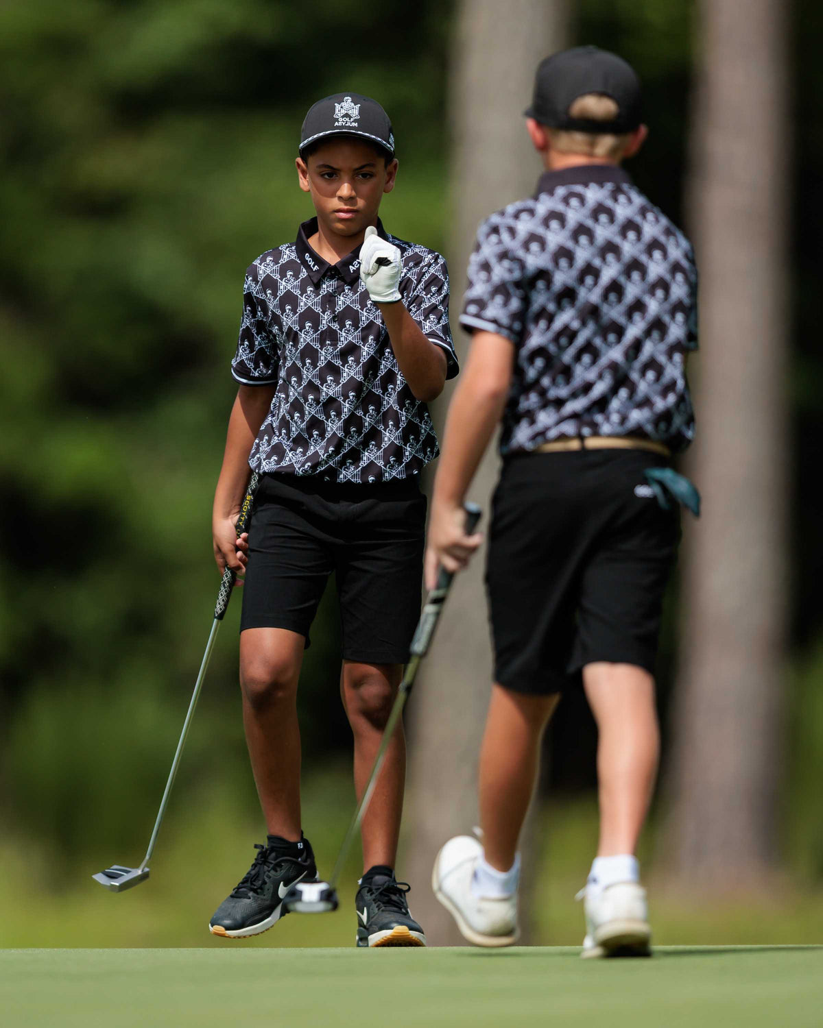 Two junior golfers about to fist-bump on the green at the Golf Asylum Invitational
